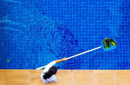 woman personnel cleaning the pool from leaves